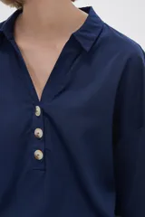 Blusa blanca holgada de poliéster con cuello camisero y mangas largas.