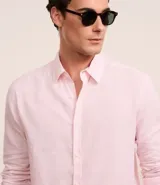 Camisa celeste de lino con cuello camisero, abotonadura frontal y mangas largas.