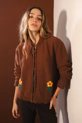 Bomber marrón de punto con cierre frontal y cuello redondo. Presenta bordados de flores amarillas y rojas en el frente.