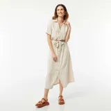 Vestido largo color beige, estilo camisero, con cuello clásico, mangas cortas, abotonadura frontal y lazo en la cintura.