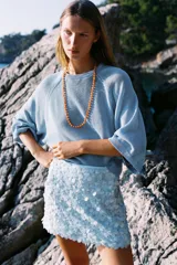 Minifalda rosada cubierta de lentejuelas, con forro interior y cierre lateral oculto.