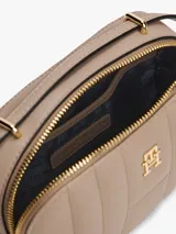 Cartera tipo clutch Tommy Hilfiger color beige con diseño acolchado, cierre de cremallera, correa de hombro y logo TH dorado en el frente.