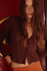 Pollera midi color naranja de tejido fluido con caída suave, elástico oculto en la cintura y bajo con leve vuelo.