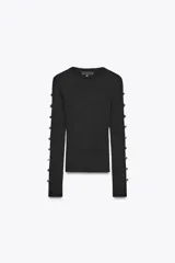 Top ajustado de punto acanalado color negro, de cuello redondo y manga larga con aberturas y botones metálicos en los brazos.