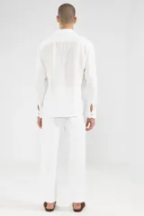Camisa blanca de manga larga confeccionada en lino 100%, con calce recto y relajado. Presenta frente abotonado con botones de coco con logo y parche con logo de la marca.