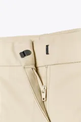 Bermuda color crema de tiro medio con pinzas delanteras y cinturón fino color beige. Tiene bolsillos frontales y falsos bolsillos de vivo en la espalda.