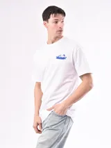 Remera blanca de algodón con cuello redondo y manga corta. Estampado en el pecho con un auto y dos figuras humanas en color azul.