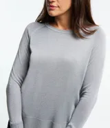 Suéter de punto color gris plateado, con cuello redondo y mangas largas. Presenta puños y bajo acanalados.