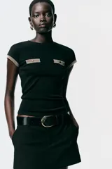 Camiseta negra de corte slim fit, cuello redondo y manga corta. Presenta falsos bolsillos en el delantero y detalle de hilo metalizado en mangas y bolsillos.