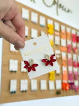 Par de aros colgantes con forma de flor, con pétalos de cristal rojo engarzados en metal dorado y centro con strass.