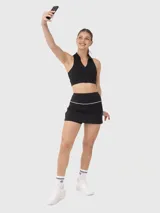 Falda deportiva negra con short incorporado y cintura alta con detalle de línea blanca.