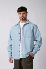 Chaqueta de jean celeste de corte recto, con cuello clásico, cierre frontal con botones metálicos y bolsillo de parche en el pecho.