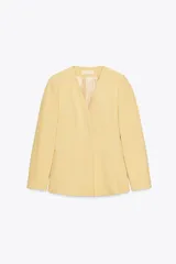 Blazer amarillo pálido de corte recto, con escote en pico y manga larga. Presenta bolsillos de ojal en el delantero y cierre frontal con botones a presión.