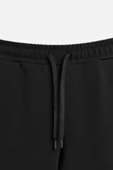Pantalón negro de corte recto confeccionado en tejido interlock de algodón con elasticidad. Tiene cintura elástica ajustable con cordón, bolsillos frontales y bolsillos traseros de vivo.