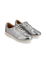 Sneaker de cuero blanco con talón dorado, cordones finos y suela beige con diseño anatómico.