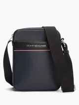 Bandolera Tommy Hilfiger de poliuretano granulado color azul marino, con correa ajustable de tejido jacquard con el logo de la marca. Tiene un compartimento principal con cierre, bolsillo interior con cremallera y bolsillo exterior abierto.