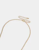 Collar corto dorado con cadena de eslabones y dijes colgantes de perlas, corazón y moño.