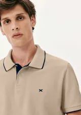 Camisa polo color rosa claro con cuello clásico, tapeta de dos botones y bordado de logo en el pecho. Presenta ribete azul marino en cuello y mangas. Corte clásico.