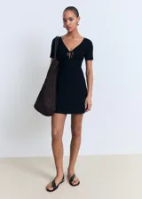 Vestido corto negro de punto fino con escote de pico y detalle de lazo.