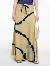 Falda larga color beige con estampado tie-dye en azul marino, lazo ajustable en la cintura y terminación desflecada en el bajo.