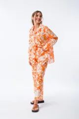 Camisa naranja con estampado floral blanco, de corte holgado, manga larga y cuello camisero.
