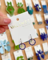 Aros de acero plateado con dije circular transparente con borde de strass azules. El diámetro del aro y del dije es de 1,5 cm.