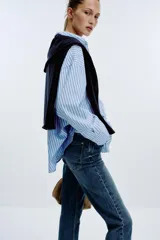 Pantalón de jean azul de tiro alto, corte mom fit, tobillero y con cinco bolsillos. Cierre frontal con cremallera y botón.