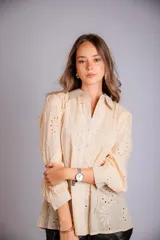 Camisa color beige con bordado inglés, de corte recto, manga larga abullonada con puño y cuello camisero.