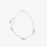 Pulsera plateada con cadena de eslabones y tres dijes de trébol de cuatro hojas con incrustaciones de circonitas.