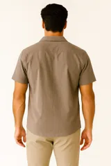 Camisa de lino color marrón, de corte holgado, con cuello tipo solapa, manga corta y cierre frontal con botones.