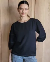 Blusa negra de mangas 3/4 con costuras decorativas en color gris claro.