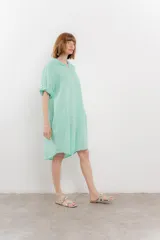Vestido camisero corto color verde oliva, confeccionado en lino 100%. Tiene botones en la parte delantera, cuello camisero, mangas cortas con botón para arremangar y bolsillos laterales.