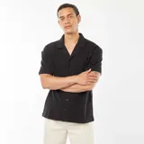 Camisa negra de manga corta con cuello remera y abotonada.