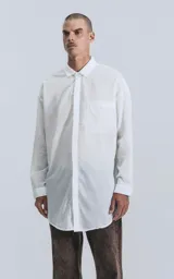 Camisa blanca de manga larga con bolsillo en el pecho, de calce oversize confeccionada en textil fresco y liviano.