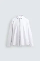 Camisa blanca de manga larga, corte slim fit, con cuello italiano y cierre frontal de botonadura.