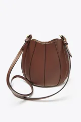 Bolso marrón formato saca con asa de mano y tira bandolera extraíble. Incluye cartera con bolsillo extraíble y cierre mediante botón imantado.