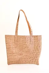 Cartera tipo tote bag de cuero color beige con textura tipo piel de cocodrilo. Tiene doble asa de hombro y un bolsillo externo con cierre.