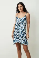 Vestido corto con estampado abstracto en colores azul, blanco y negro. Cuenta con tirantes finos, escote redondo y detalle de volado en el ruedo.