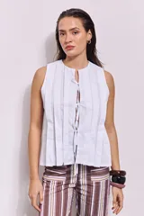 Blusa blanca sin mangas con cuello redondo y detalle de lazo en el frente.
