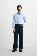 Camisa celeste de corte slim fit, confeccionada en tejido de algodón. Tiene cuello italiano, mangas largas con puños abotonados y cierre frontal con botones.