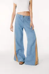 Pantalón de jean negro de pierna ancha con cortes en los laterales que van desde la pretina al bajo del pantalón. Por la mitad de la pierna presenta godets triangulares de encaje para darle mayor amplitud y detalles a la prenda.