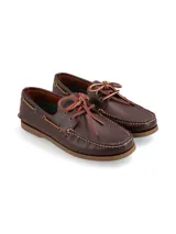 Zapato náutico de cuero color marrón oscuro, con cordones de cuero marrón claro y suela de goma color caramelo.