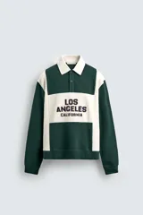 Polo relaxed fit verde oscuro con detalles en blanco, cuello solapa con cierre frontal de botonadura y manga corta. Bordado frontal con la inscripción "Los Angeles California".