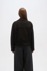 Chaqueta negra con cuello solapa, cierre cruzado con cremallera, cinturón con hebilla, bolsillos laterales con cremallera y detalles de botones metálicos.