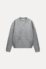 Sweater gris de punto con escote en V y manga larga.