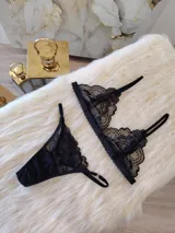 Conjunto de lencería negro de encaje, compuesto por un bralette con breteles regulables y una tanga regulable con corte cola less y entrepierna de algodón.