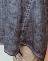 Top sin mangas blanco de lino, con escote redondo, corte en A, ruedo asimétrico y recortes laterales.