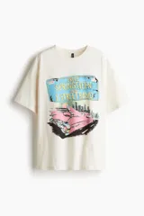 Remera color crema de corte oversized, con estampado de una patente con el nombre de Bruce Springsteen y un auto clásico rosa. Cuello redondo ribeteado.
