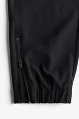 Pantalón de correr negro de tejido funcional DryMove™, corte estándar, cintura elástica con cordón, bolsillos laterales con cierre oculto, piernas levemente ajustadas con elástico revestido y cierre en los bajos. Stretch en cuatro direcciones.