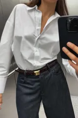 Camisa celeste de popelina de algodón, con cuello solapa, escote pico, manga larga con puños y cierre frontal con botones.